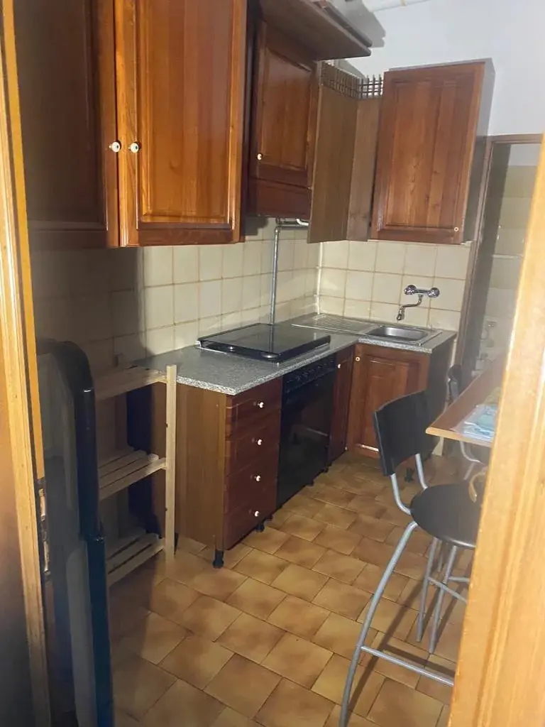 המטבח הישן של הדירה: ארונות עץ כהים ואריחים ישנים